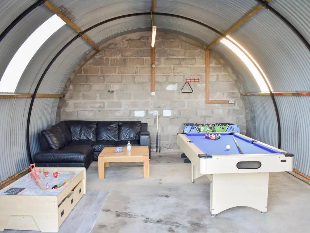 a living room with a couch and a pool table at Benwells Holiday Cottage in Maud
