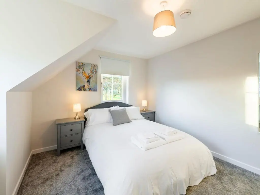 a bedroom with a white bed and a window at Holiday Home Loch Ness House by Interhome in Drumnadrochit