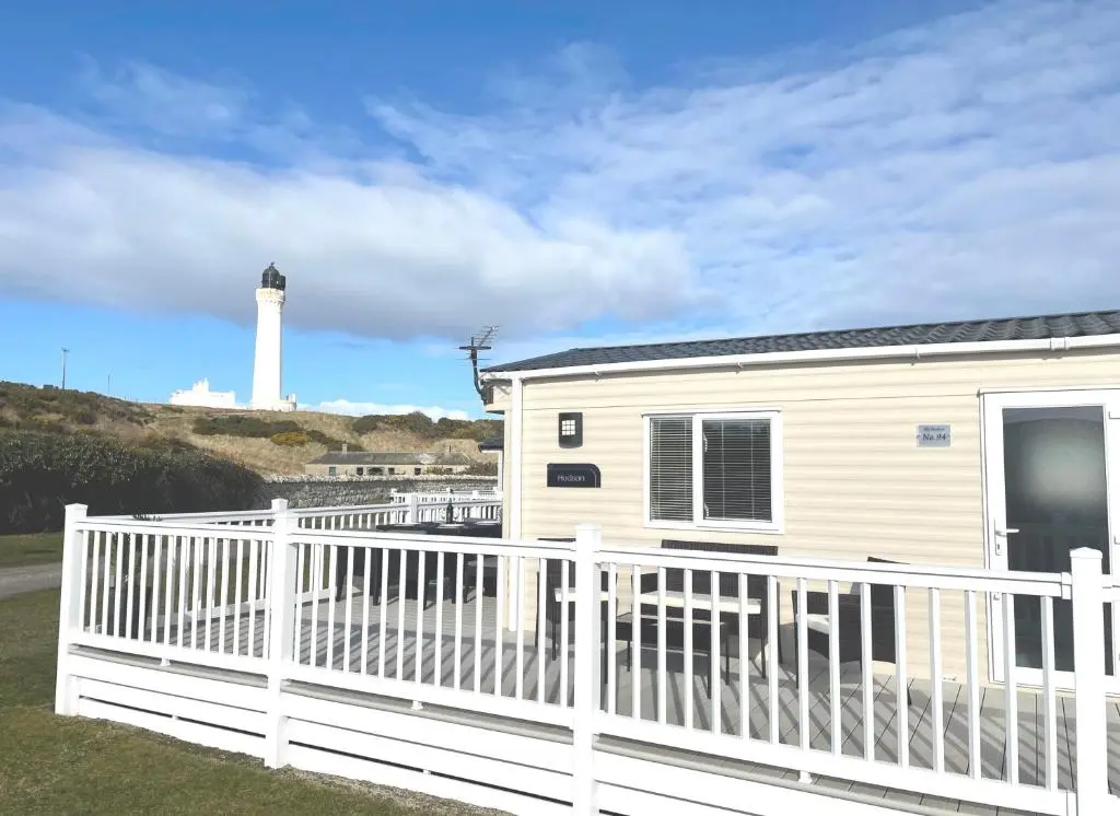 a house with a white fence and a lighthouse at The Hudson @ Silversands in Lossiemouth