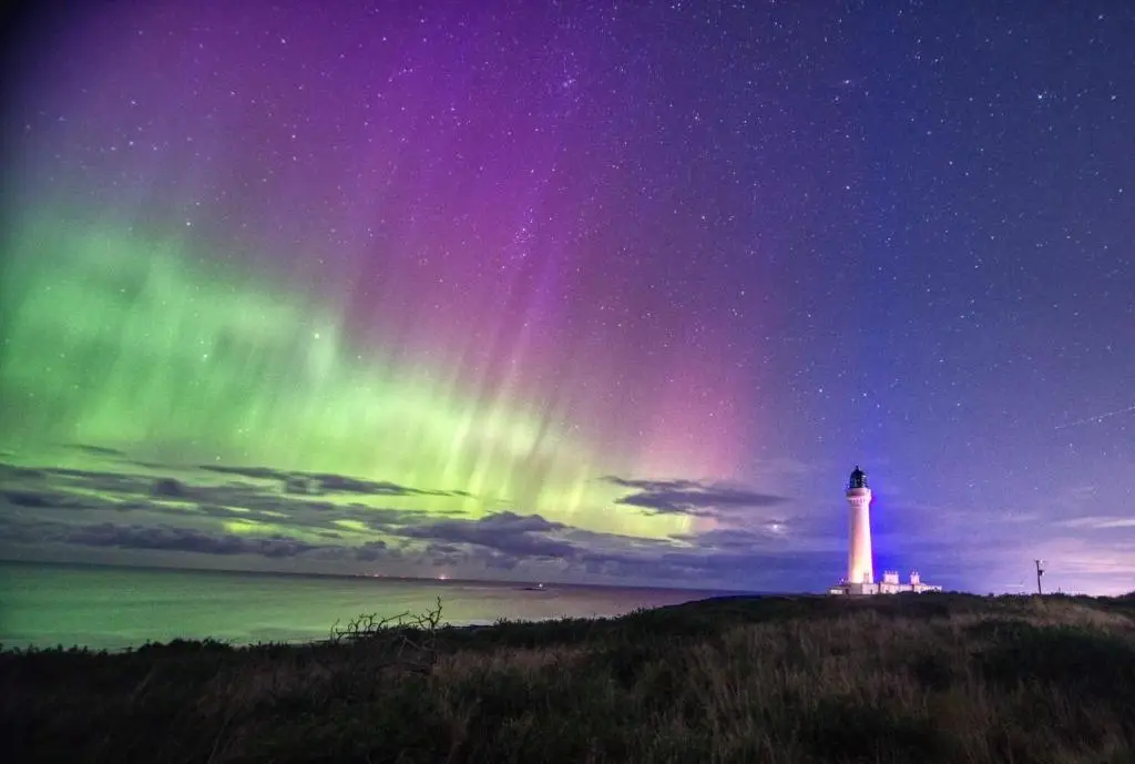 a light house with the aurora in the sky at The Hudson @ Silversands in Lossiemouth