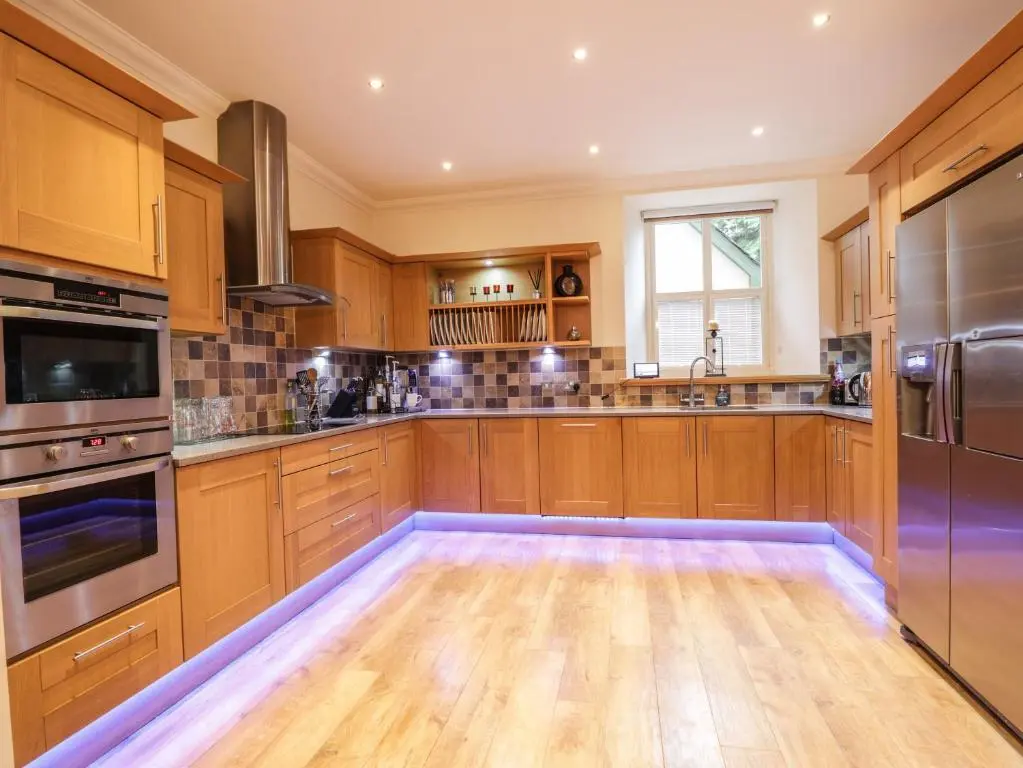 a kitchen with wooden cabinets and stainless steel appliances at 1 The Coach House in Elgin