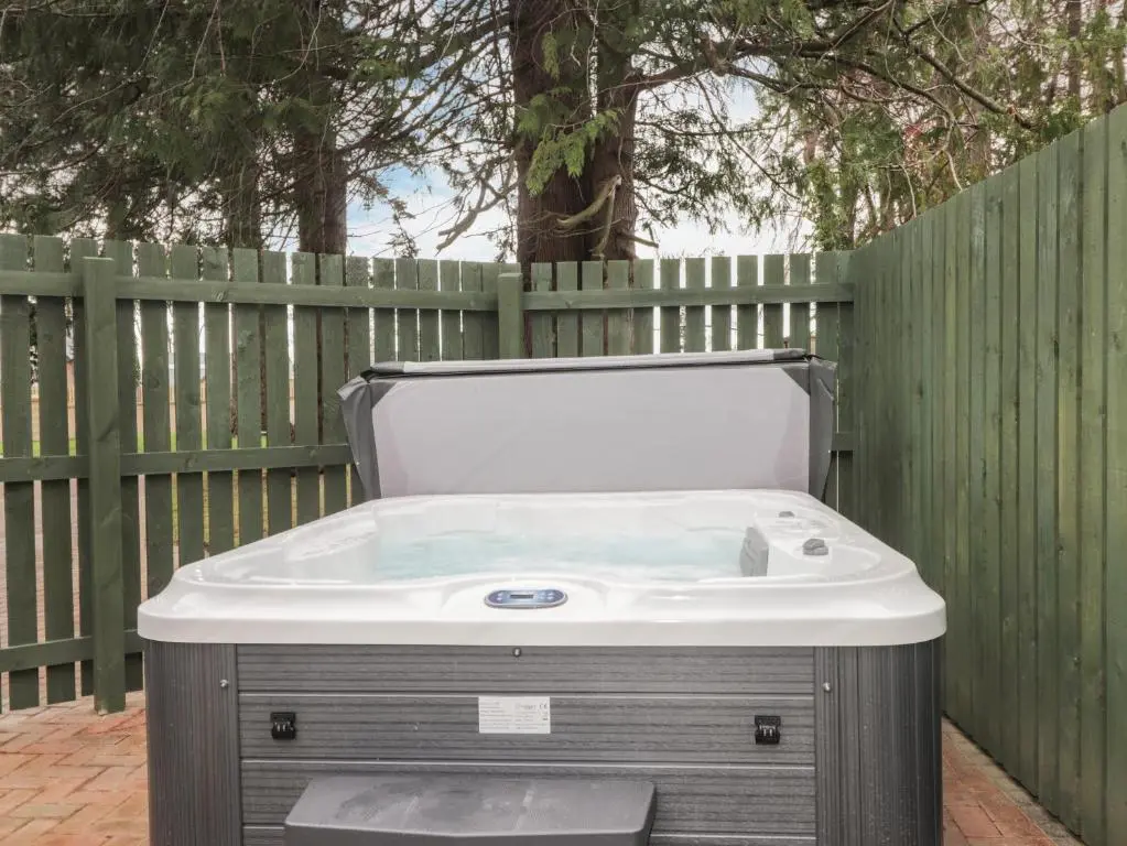 a hot tub sitting in front of a fence at 1 The Coach House in Elgin