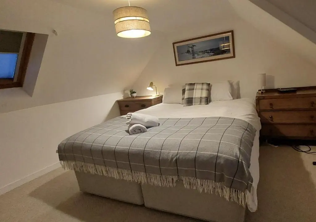 a bedroom with a bed with a teddy bear on it at Wee Blondie's Ski Cottage in Aviemore