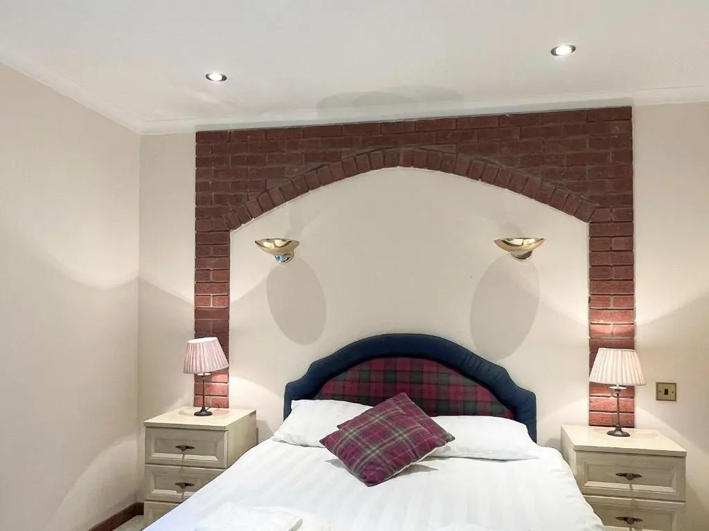 a bedroom with a bed with a brick wall at Oich View - Uk37554 in Kilfinnan