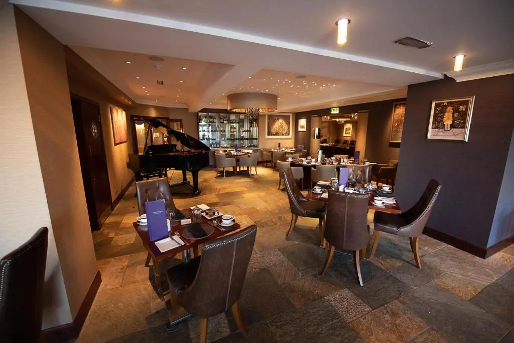 a restaurant with tables and chairs and a piano at The Mansefield Hotel in Elgin