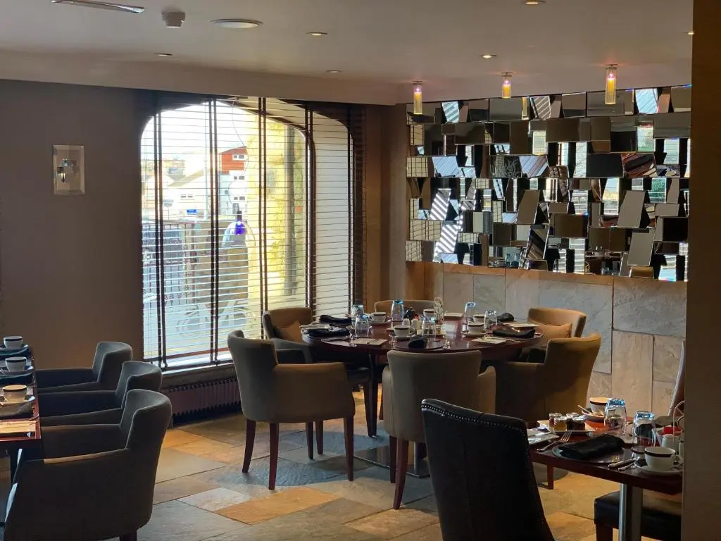 a restaurant with tables and chairs and a large window at The Mansefield Hotel in Elgin
