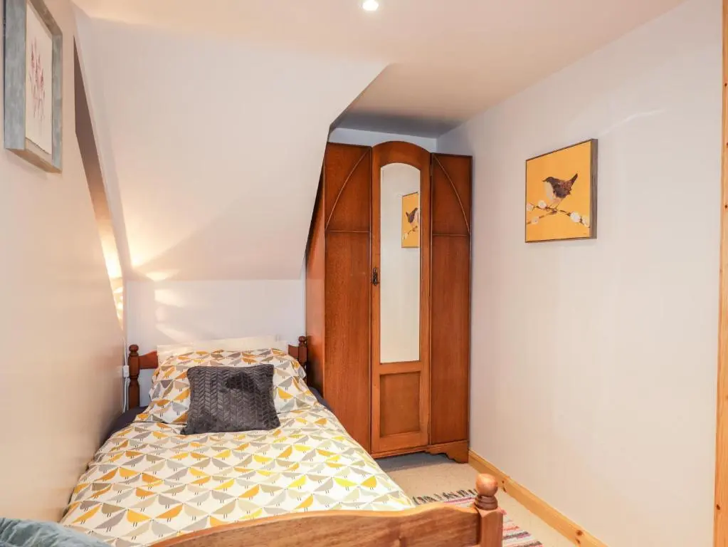 a bedroom with a bed and a wooden door at Bogindour Cottage in Muir of Ord