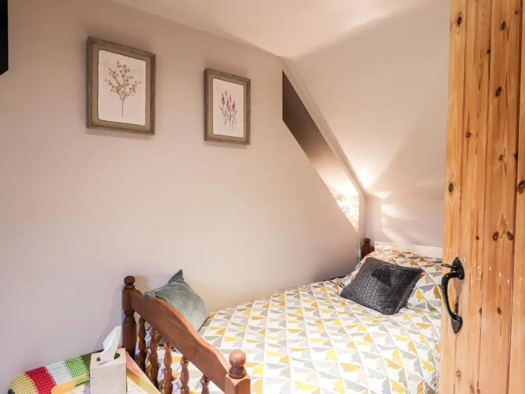 a bedroom with a bed and two pictures on the wall at Bogindour Cottage in Muir of Ord