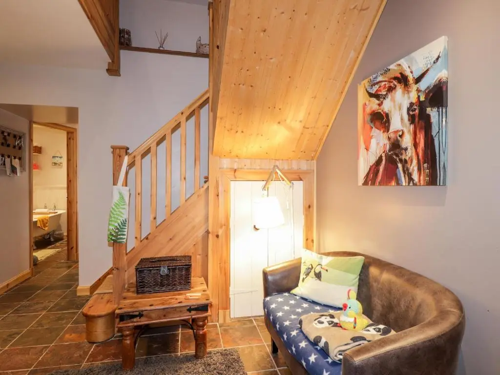 a living room with a couch and a staircase at Bogindour Cottage in Muir of Ord