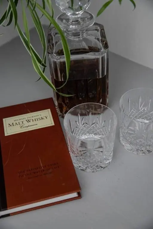 a book sitting next to two glasses and a vase at Whitecraigs in Elgin