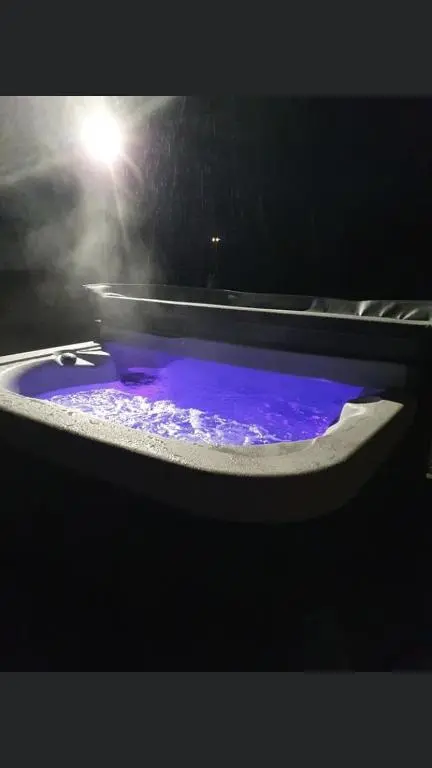 a bath tub filled with purple water with a light at Robins Nest Glamping Pod with Hot Tub in Keith