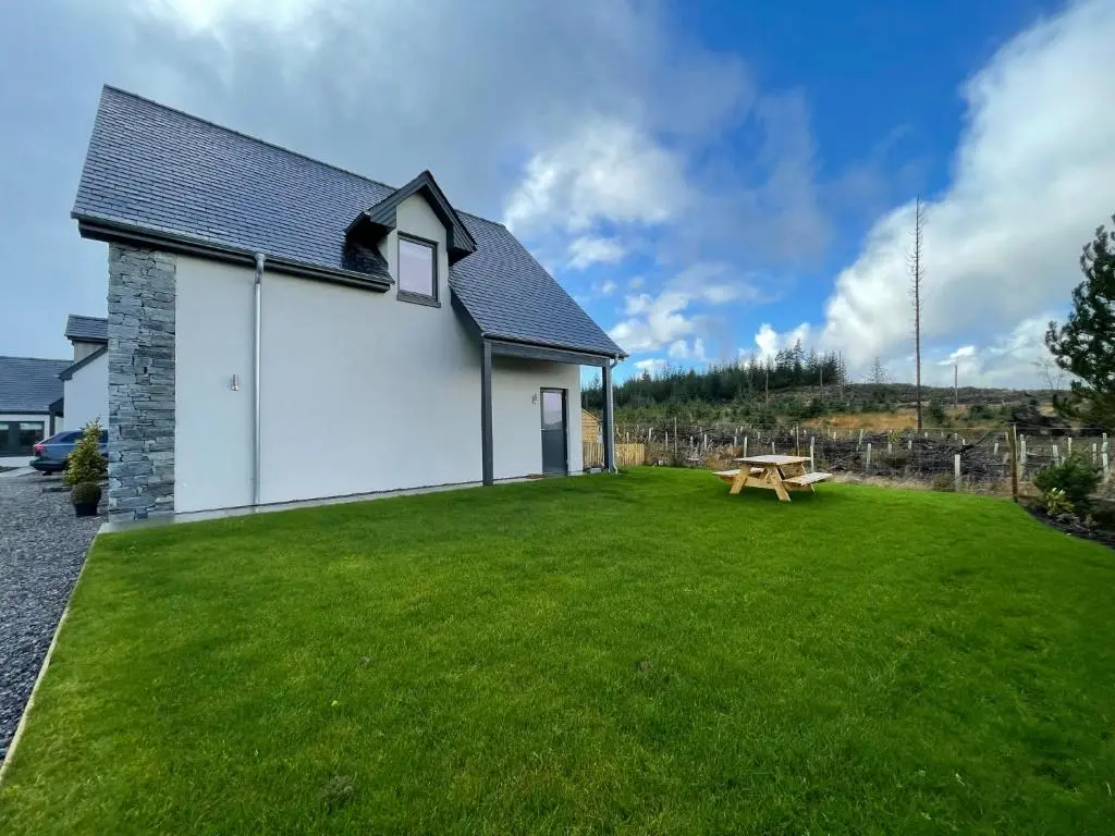 a white building with a picnic table in a yard at Little Thistle Apartment in Whitebridge