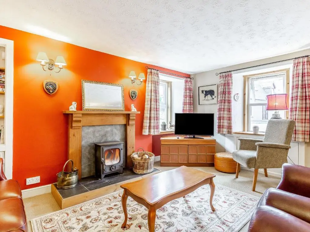 a living room with orange walls and a fireplace at Holly Tree Cottage in Tain
