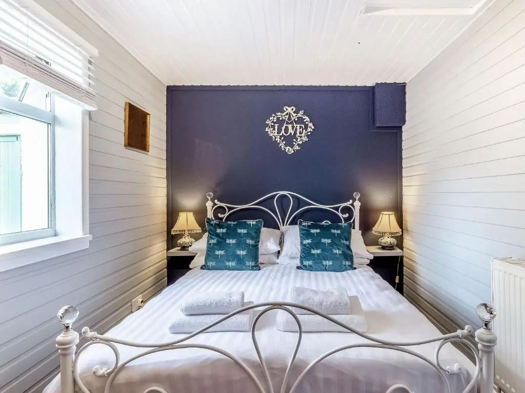 a bedroom with a bed with a blue wall at Holly Tree Cottage in Tain