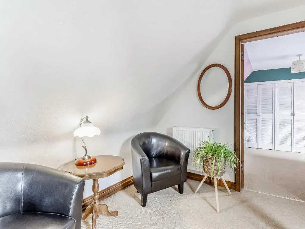 a living room with a chair and a table at Holly Tree Cottage in Tain
