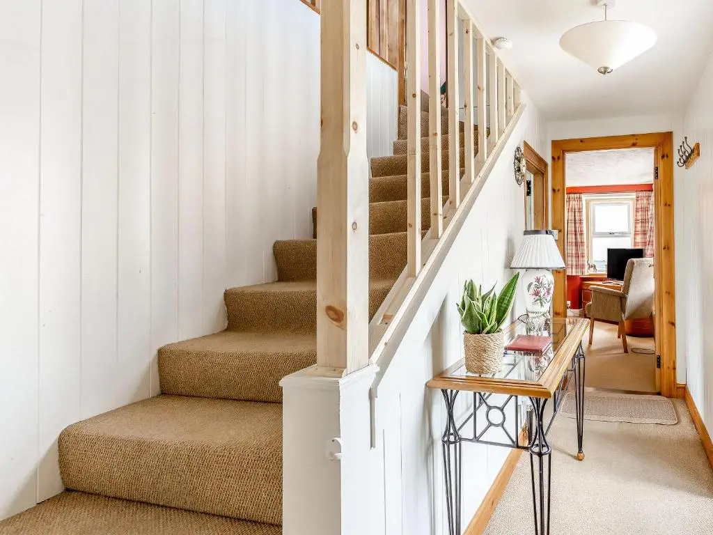 a staircase in a home with white walls at Holly Tree Cottage in Tain