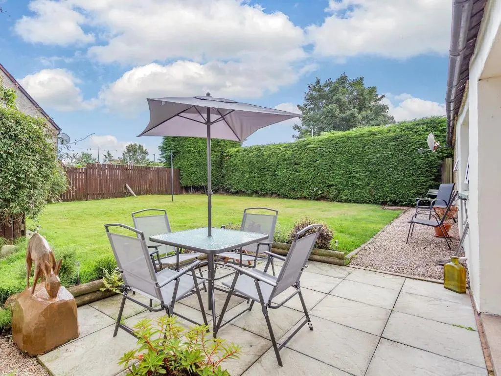 a table and chairs with an umbrella on a patio at Holly Tree Cottage in Tain