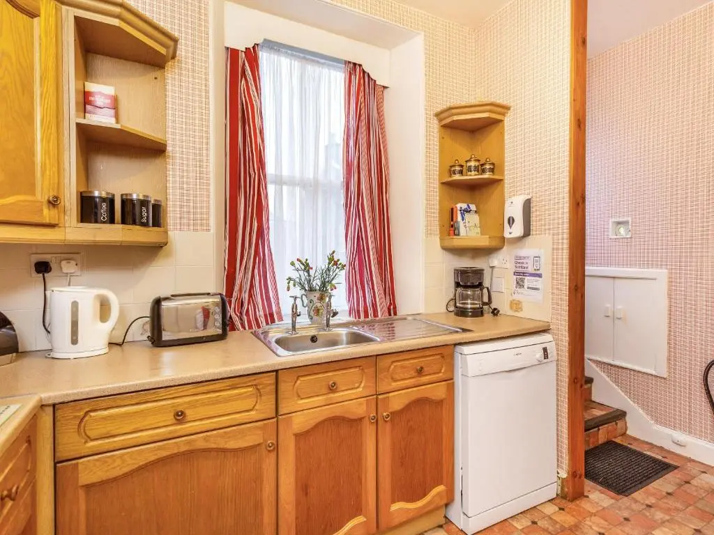 a kitchen with wooden cabinets and a sink and a window at Isla Bank Cottage in Keith