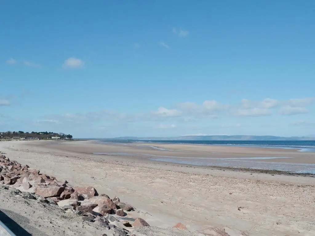 a beach with rocks on the sand and water at Isla Bank Cottage in Keith