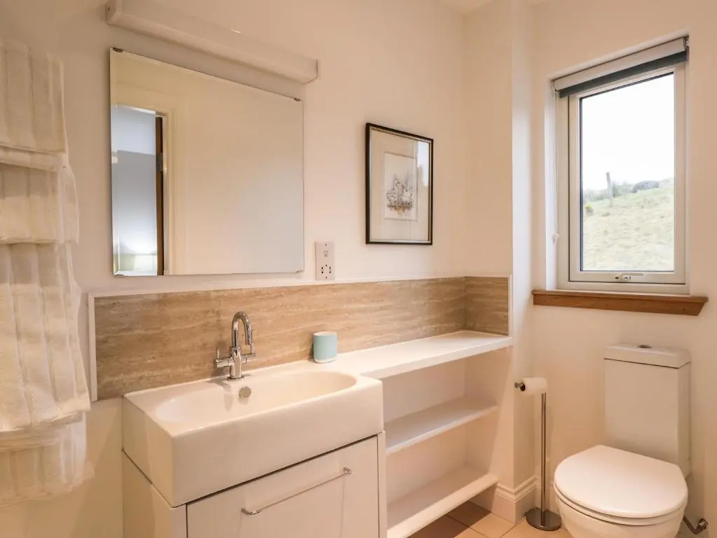 a bathroom with a sink and a toilet and a mirror at Sealladh Mor in Rogart