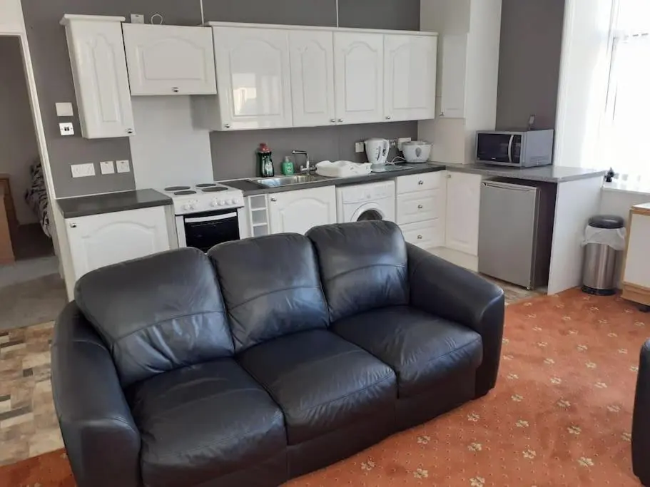 a living room with a leather couch in a kitchen at Lossiemouth Seaside Flat in Lossiemouth