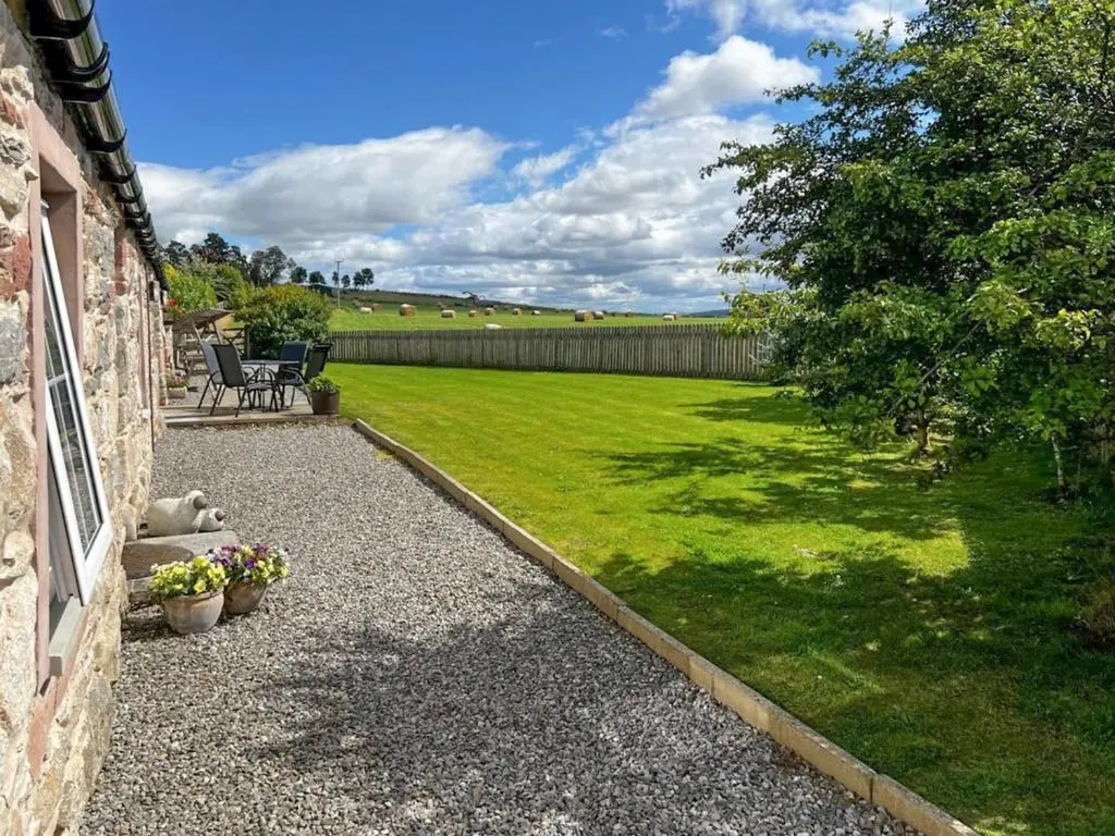 a backyard with a lawn and a yard with a house at Paterson Cottage in Tore