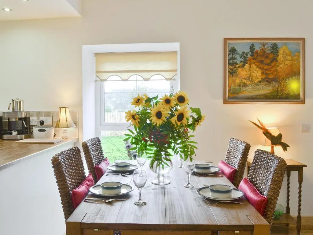 a dining room table with a vase of sunflowers at Paterson Cottage in Tore