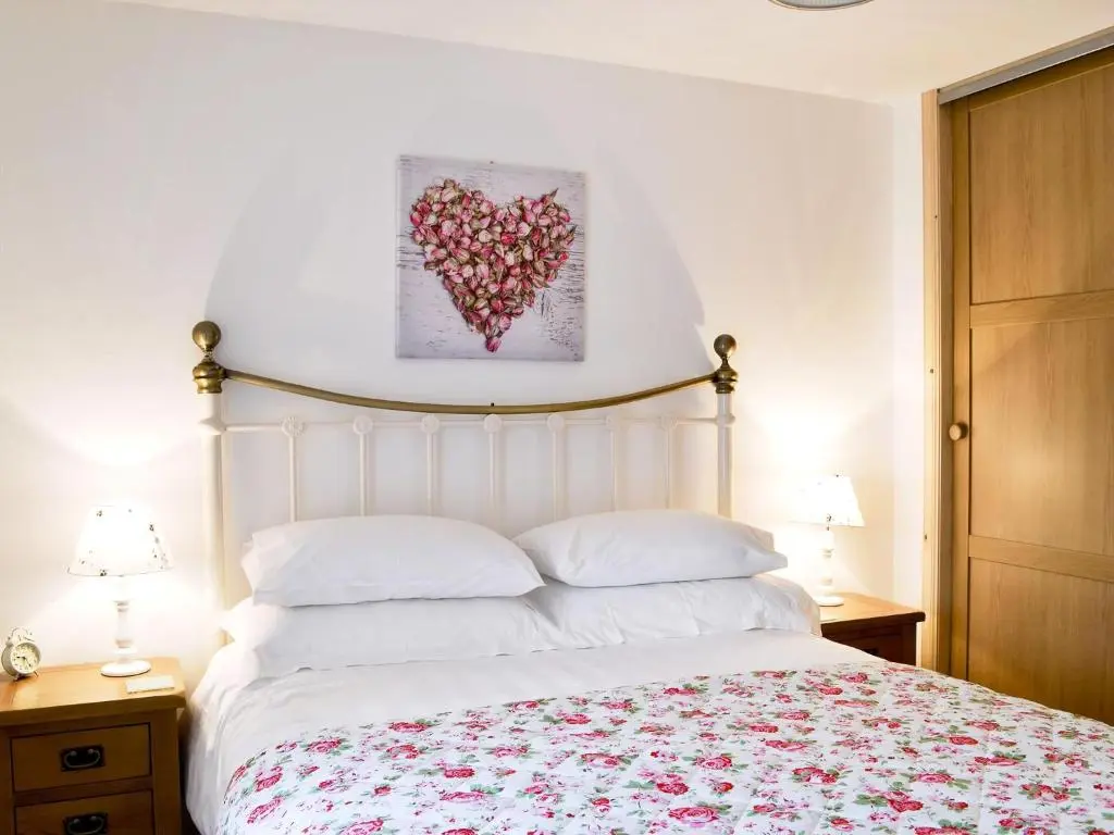 a bedroom with a bed with a heart painting on the wall at Paterson Cottage in Tore