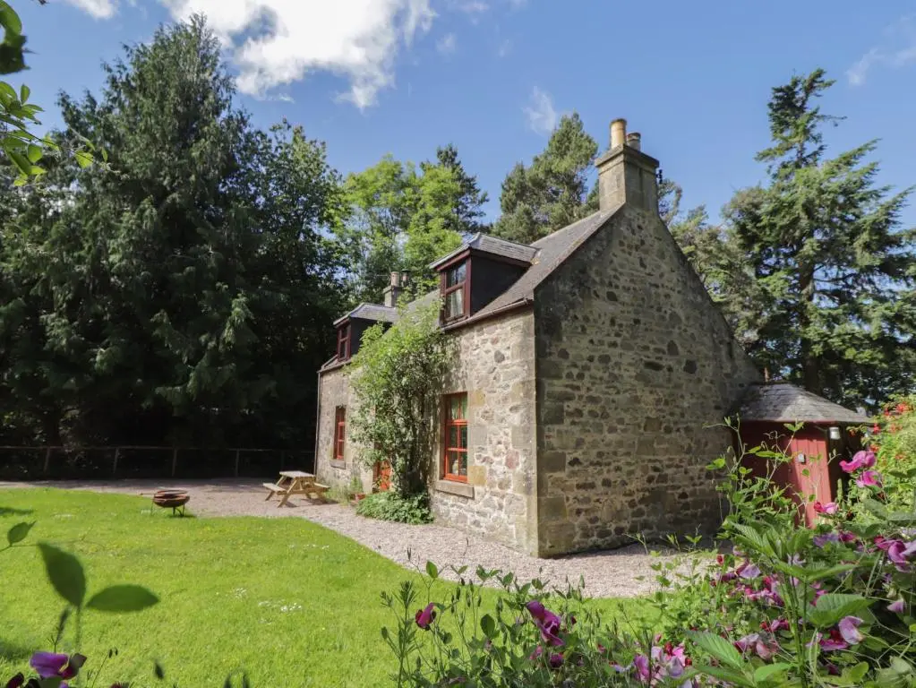 a stone cottage in a garden with flowers at The Mains in Elgin