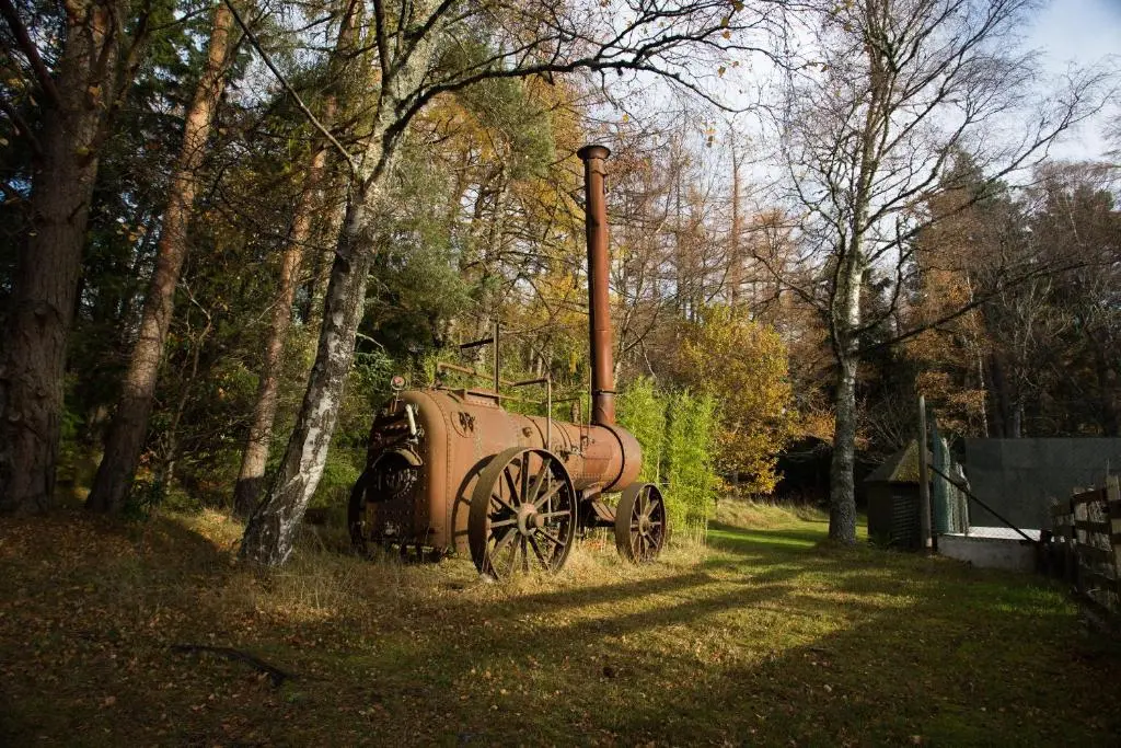 an old truck is sitting in the grass near trees at The Mains in Elgin