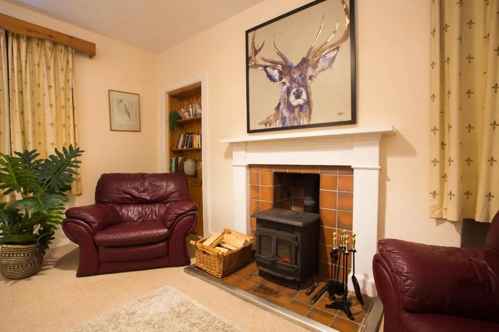a living room with a fireplace and a picture of a deer at The Mains in Elgin