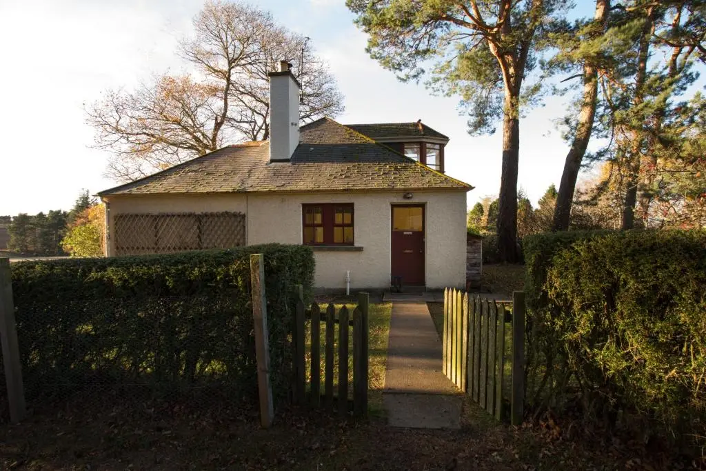 a small white house with a gate and a fence at The White Cottage in Elgin