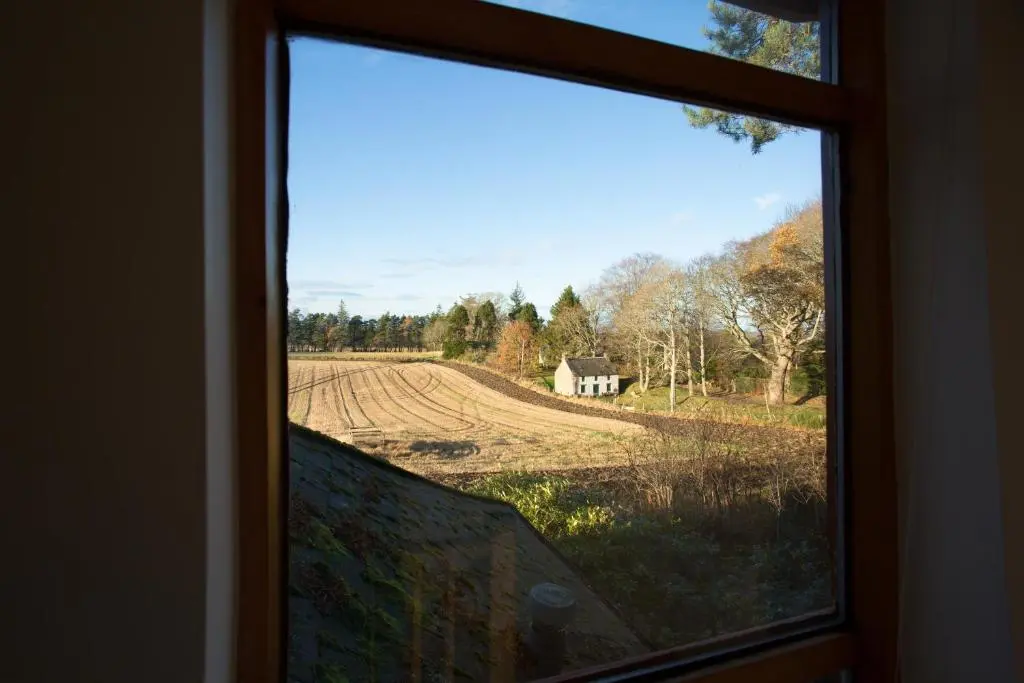 a window with a view of a farm field at The White Cottage in Elgin