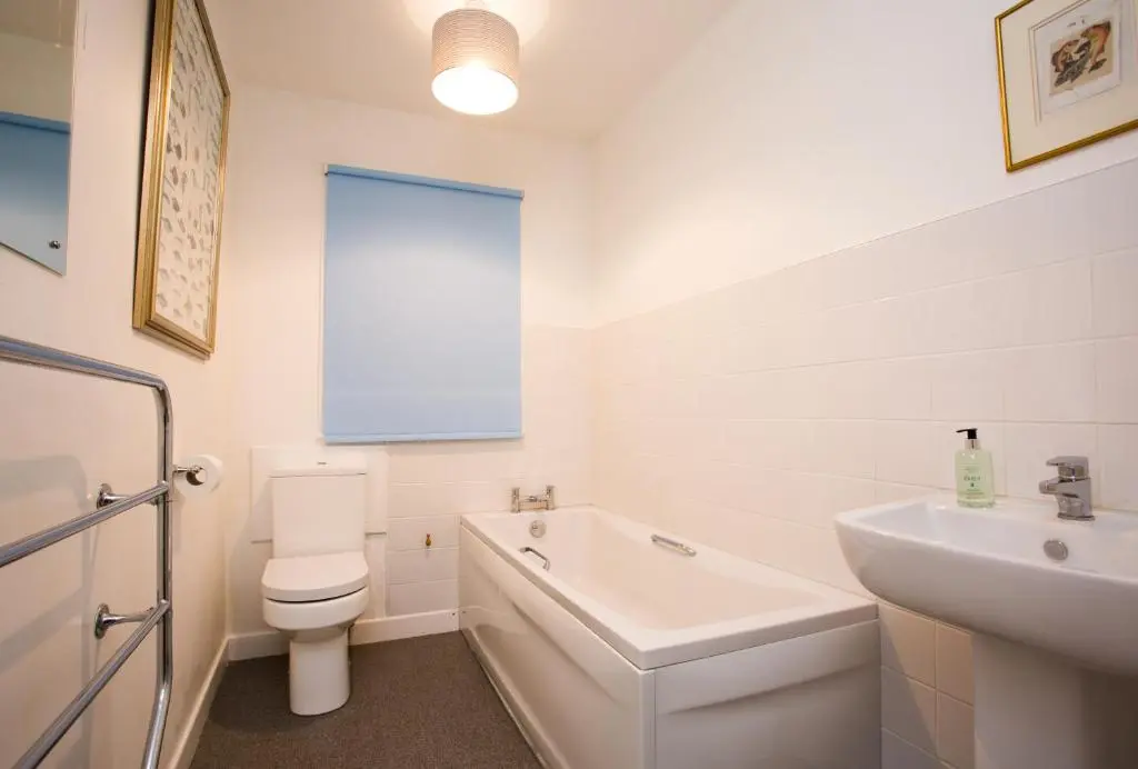 a white bathroom with a toilet and a sink at The White Cottage in Elgin