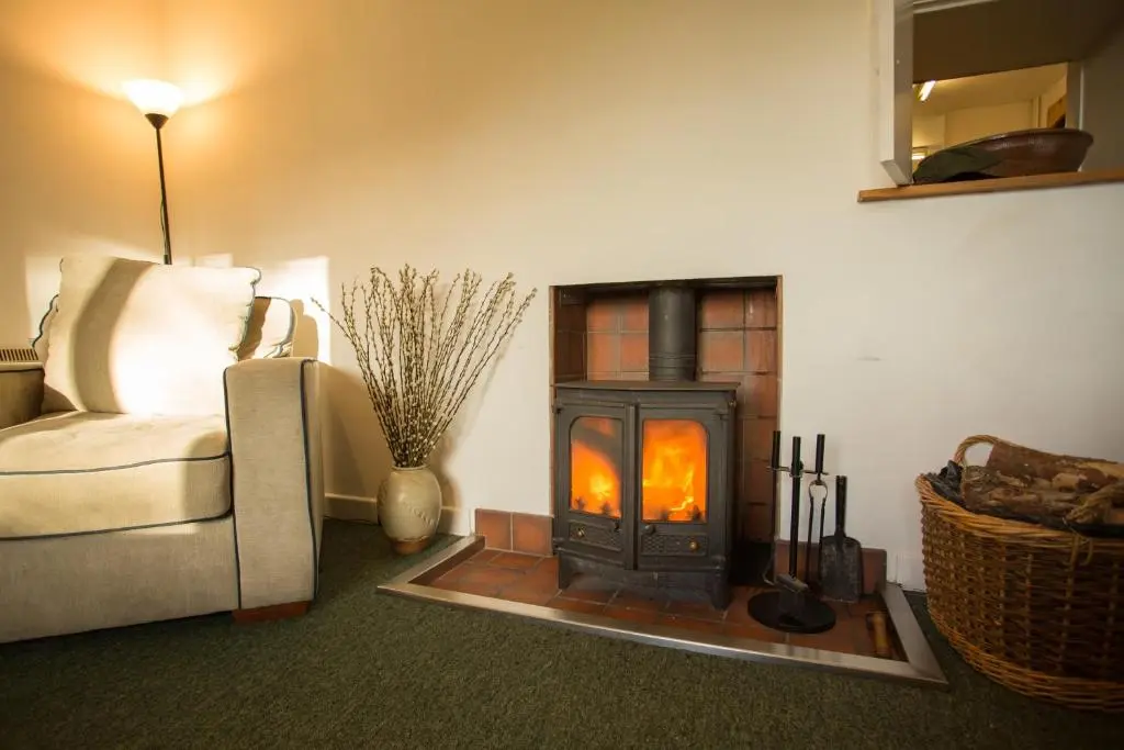 a living room with a wood stove in a room at The White Cottage in Elgin