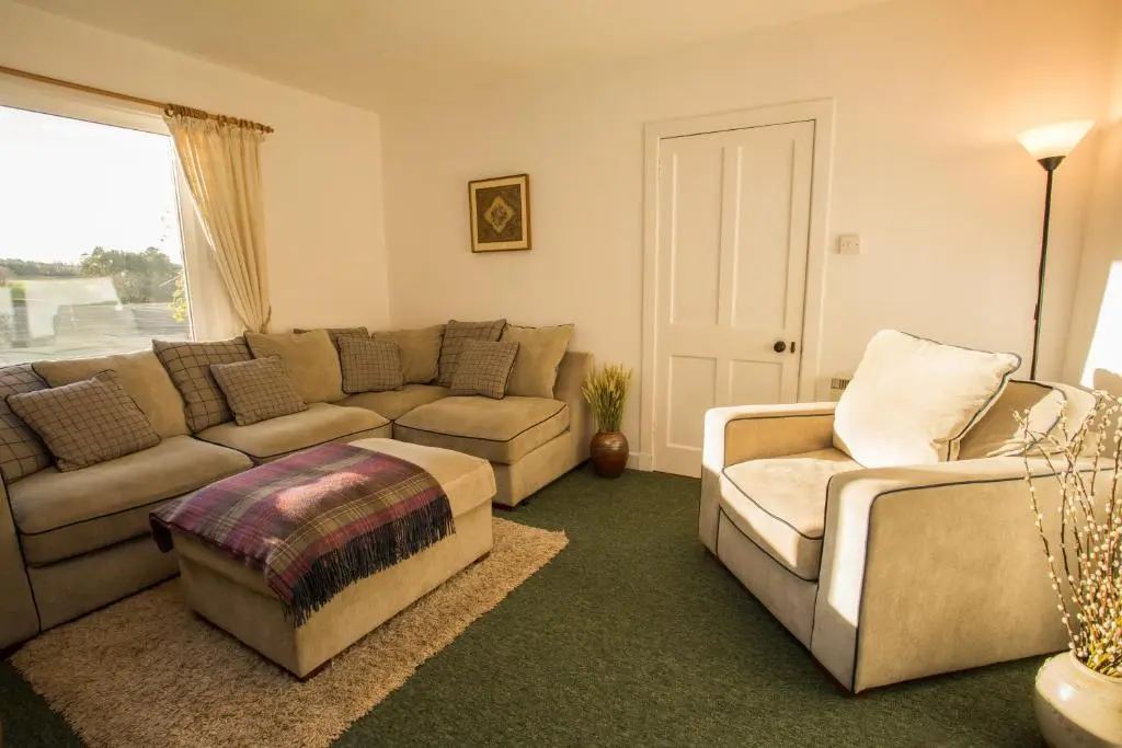a living room with a couch and a chair at The White Cottage in Elgin
