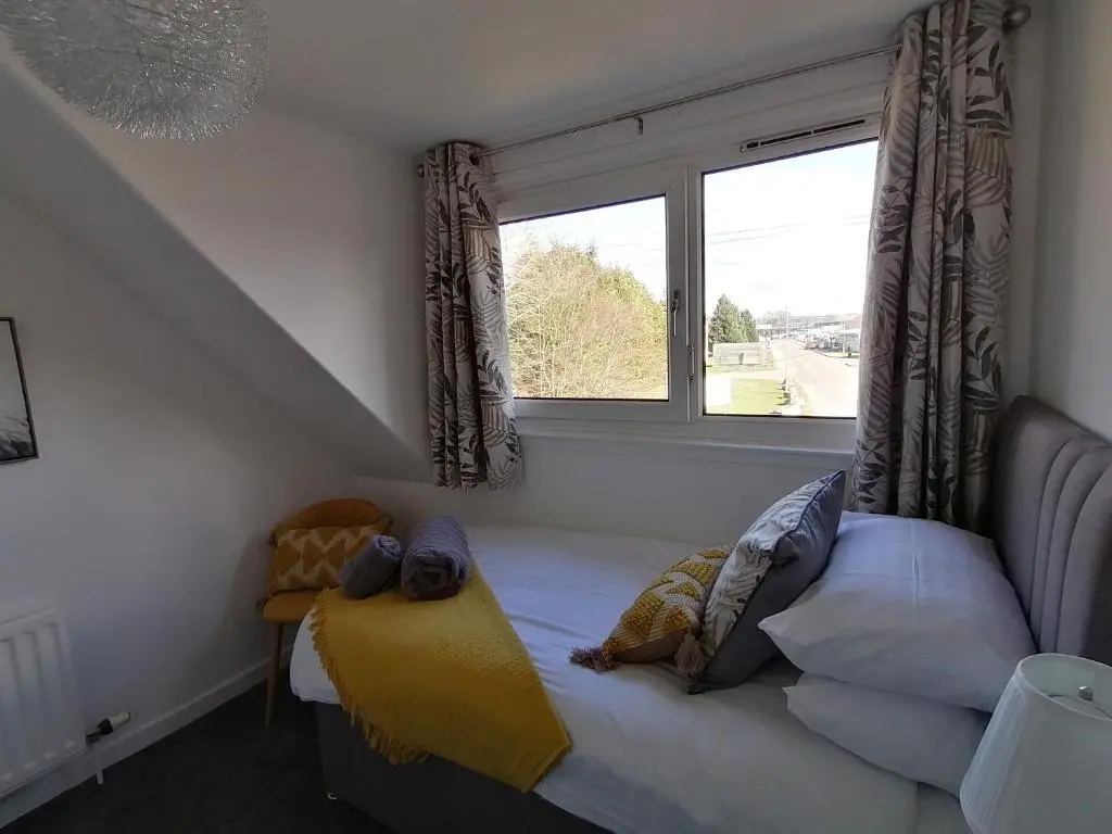 a bed in a room with a window at Delightful, central 3 bedroom house with garden & free parking in Inverness