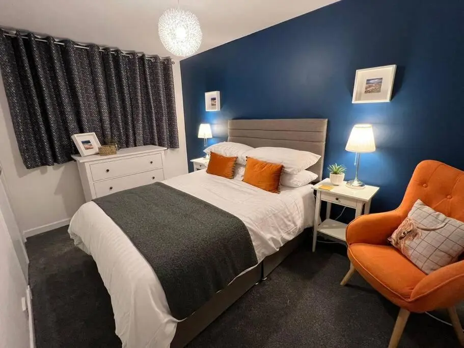 a bedroom with a bed and an orange chair at Delightful, central 3 bedroom house with garden & free parking in Inverness