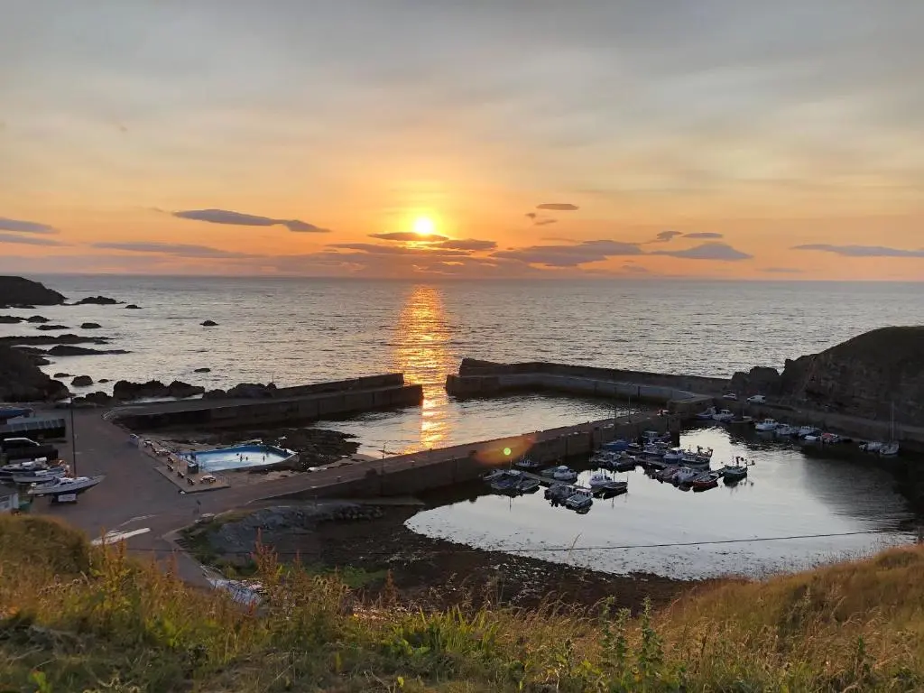 a sunset over a harbor with boats in the water at 4 Gordon Street in Buckie