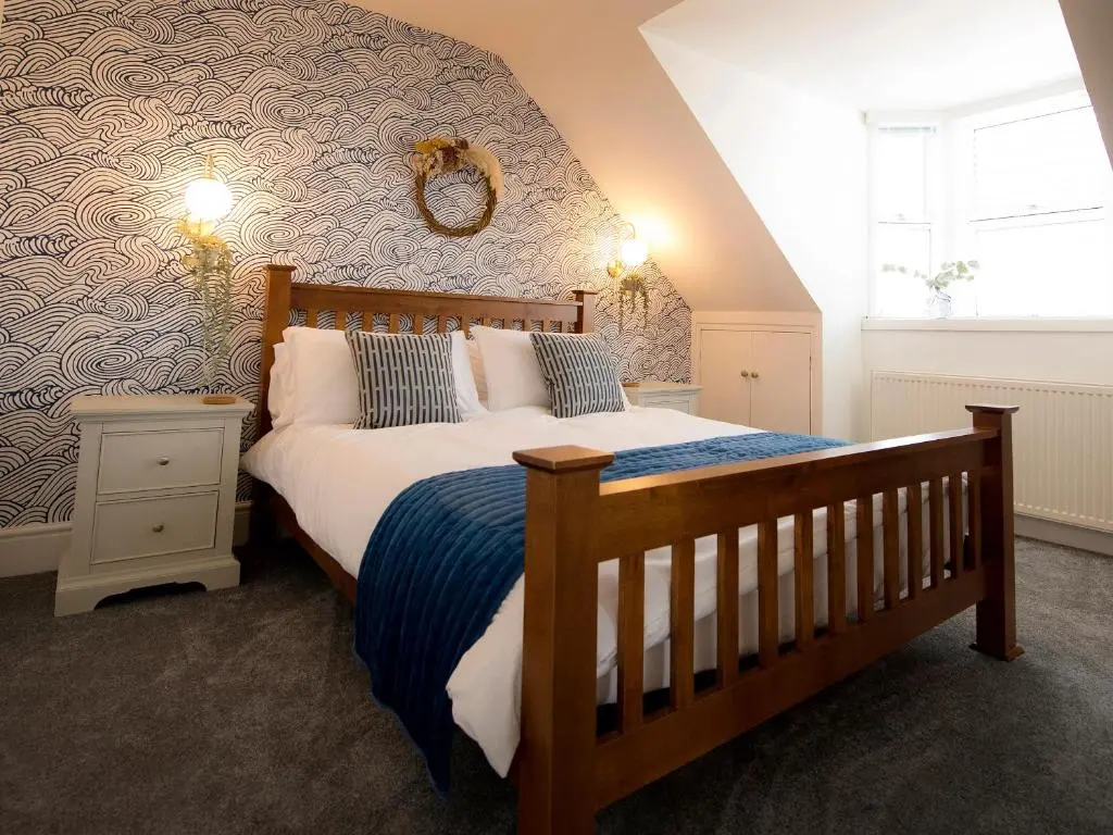 a bedroom with a bed with a blue and white comforter at Sandpiper Cottage in Buckie