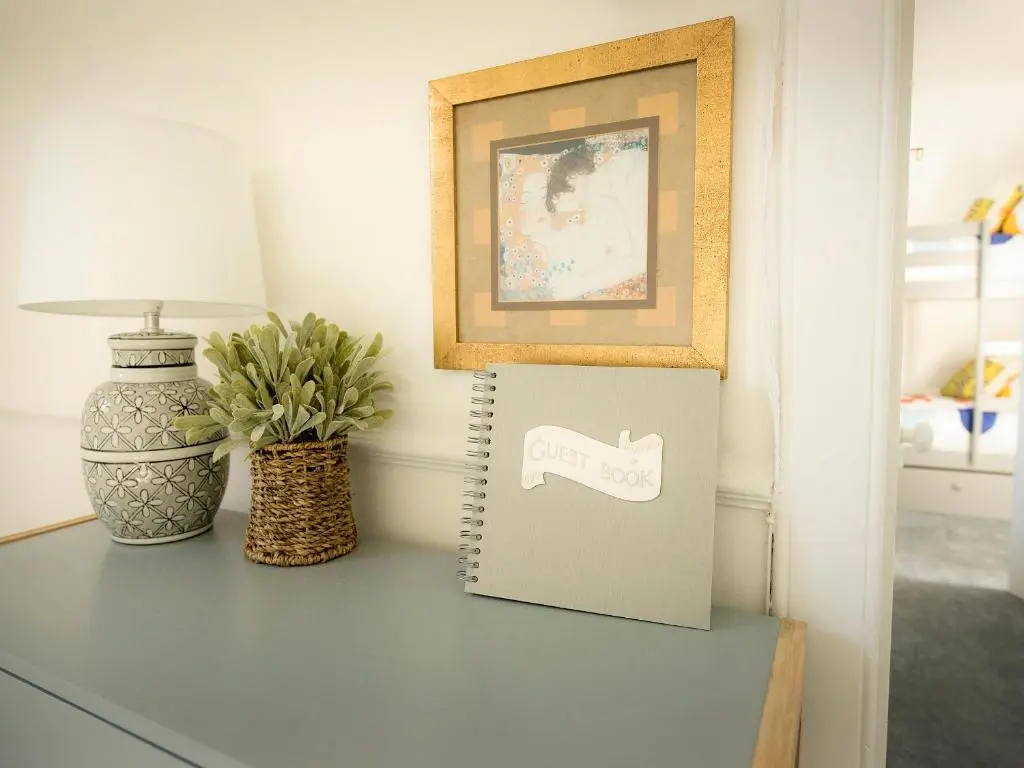 a table with a notebook and a picture and a vase at Sandpiper Cottage in Buckie