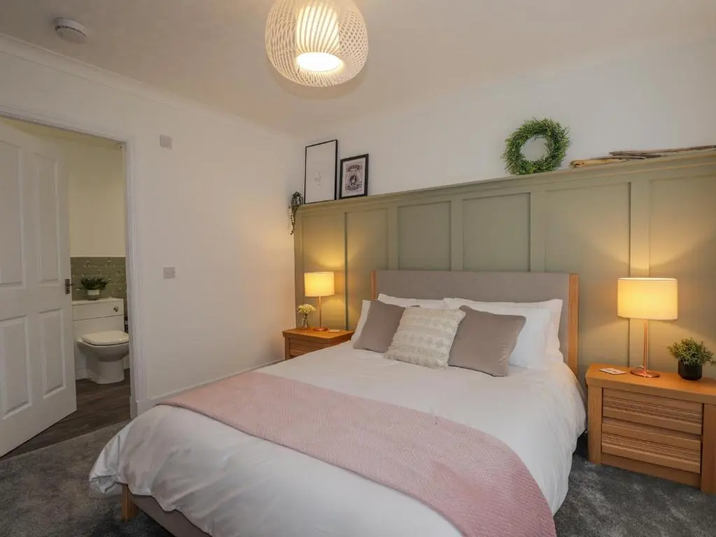 a bedroom with a large bed and a bathroom at Sandpiper Cottage in Buckie