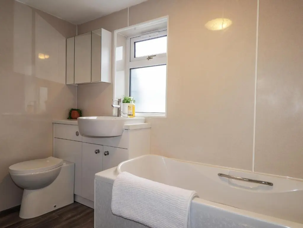 a bathroom with a tub and a toilet and a sink at Sandpiper Cottage in Buckie