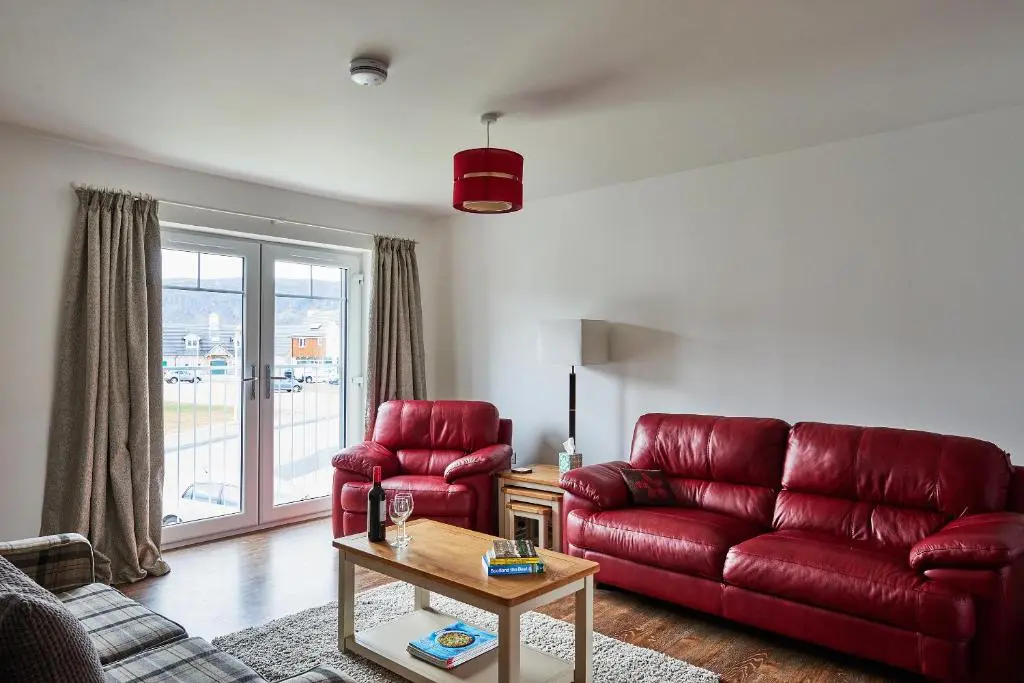 a living room with a red couch and a table at Aviemore apartment (pet friendly) - sleeps 4 in Aviemore
