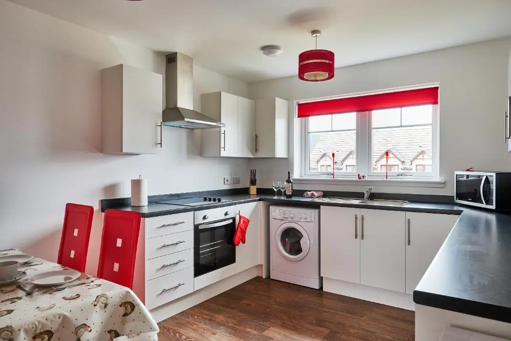 a kitchen with white cabinets and a washing machine at Aviemore apartment (pet friendly) - sleeps 4 in Aviemore