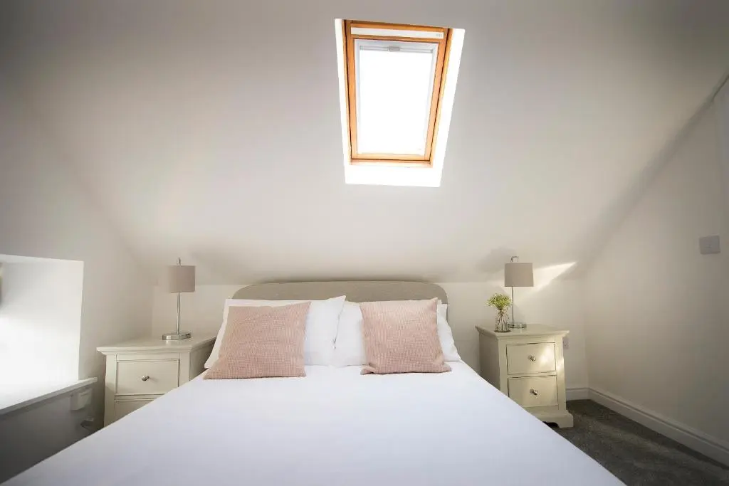 a bedroom with a white bed and a window at Eider Cottage in Buckie