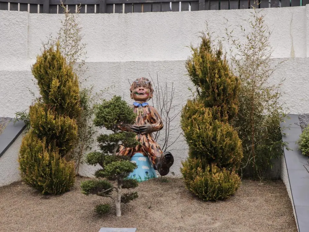 a statue of a woman on a vase in a garden at Eider Cottage in Buckie