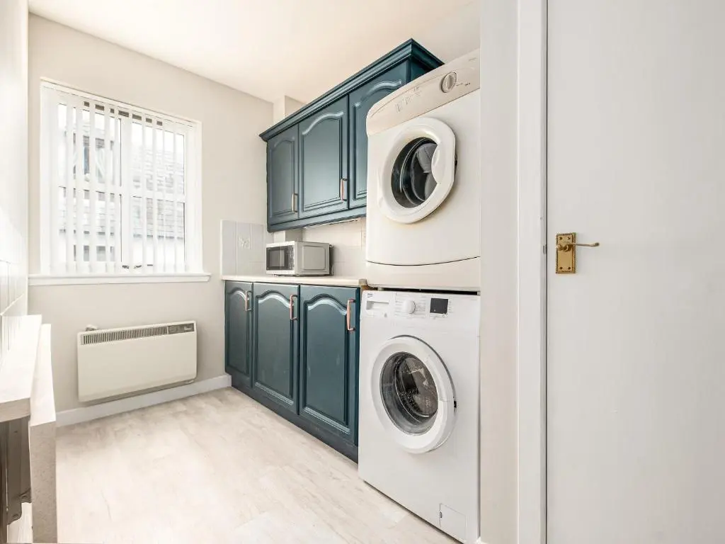 a laundry room with green cabinets and a washer and dryer at By The Sea in Avoch
