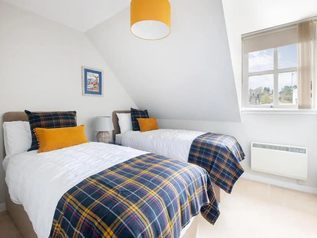 a bedroom with two beds and a window at By The Sea in Avoch