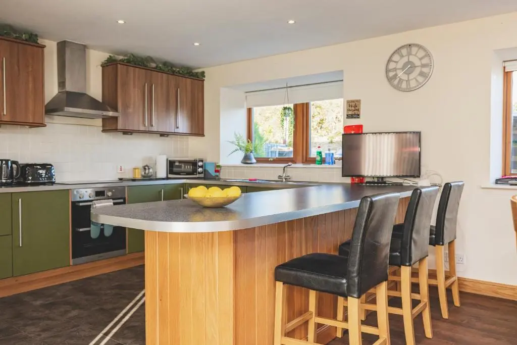 a kitchen with a island with bar stools at Stunning Country House - Cinema, Games Room & Hot Tub in Inverurie